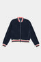 A 100% polyester navy blue fleece jacket with a front zipper, featuring red, white, and blue striped cuffs, collar, and hem. The product is called the Willa Sherpa Jacket - Indigo by SPLITS59.