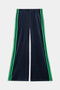 The SPLITS59 Heritage Velour Pant in Indigo/Grass features wide legs with two green side stripes, crafted from navy velour fabric and shown laid flat on a white background.