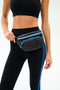 A person wears a black sports bra and black leggings with blue stripes, posing with the SPLITS59 MZW x Splits59 Small Metro Sling quilted black fanny pack strapped at the waist.