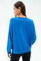 A woman with straight brown hair, seen from the back against a white background, wears the SPLITS59 Andie Oversize Fleece Sweatshirt in Classic Blue with black leggings.
