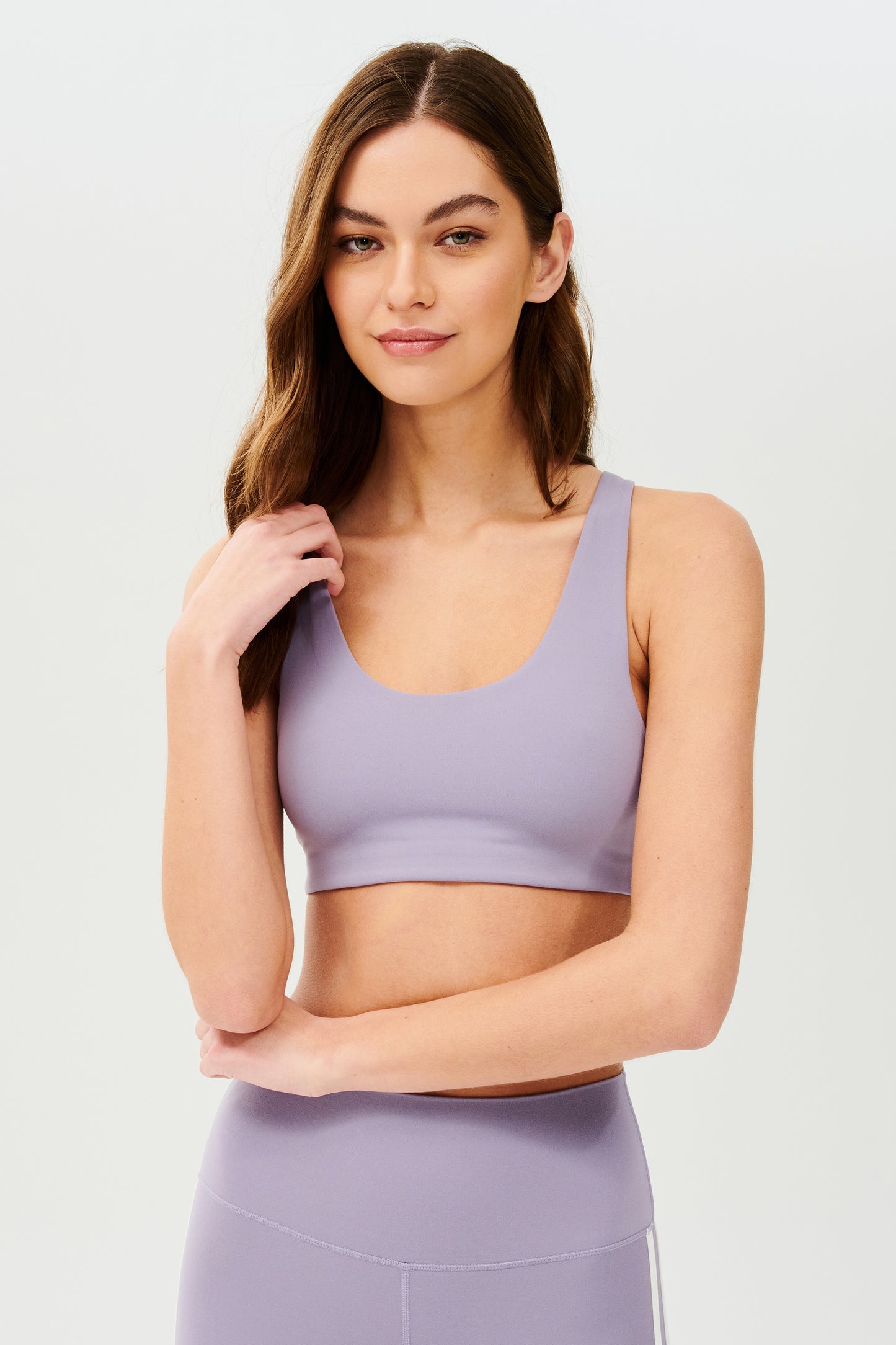 Front view of girl wearing light purple sports bra with two thin white stripes down the side and light purple leggings