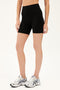 Front  side view of model wearing black high waist bike shorts paired with white shoes with black stripes