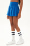 Side view of girl wearing blue upper thigh skirt with built in shorts and white shoes