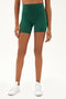 Front view of girl wearing highwaisted mid thigh green bike shorts with white shoes
