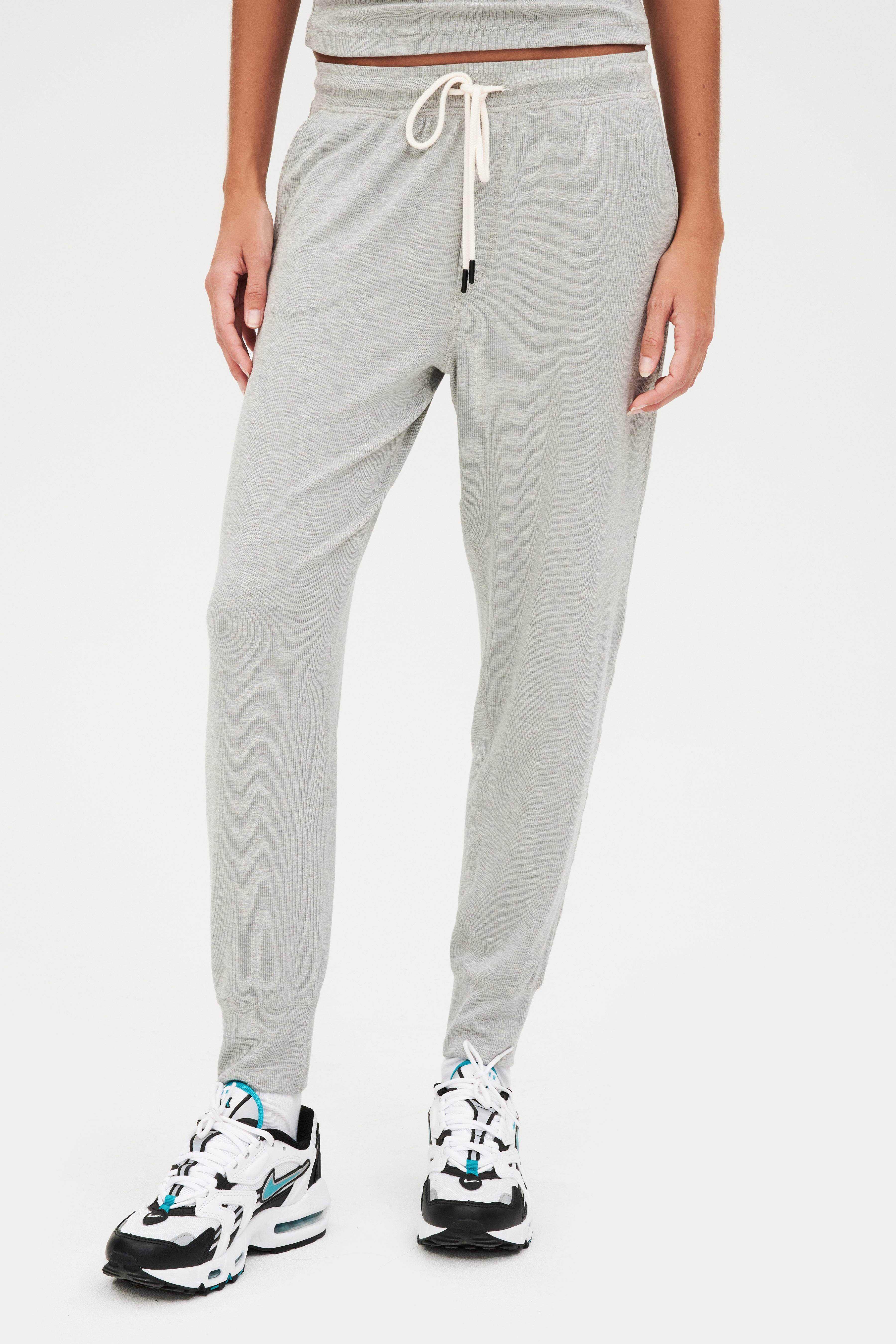 A woman wearing comfortable, SPLITS59 Kiki Rib 7/8 Sweatpant in Heather Grey and sneakers.