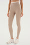 Person wearing ultra luxe, SPLITS59 Dual High Waist Airweight 7/8 - Latte/White leggings and white sneakers, standing against a plain white background.
