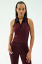 A woman wears the SPLITS59 Austin Airweight Crop Polo in Dark Cherry/Indigo, a sleeveless maroon athletic top with a collar, paired with matching leggings, made from soft nylon and spandex, standing against a plain light background.