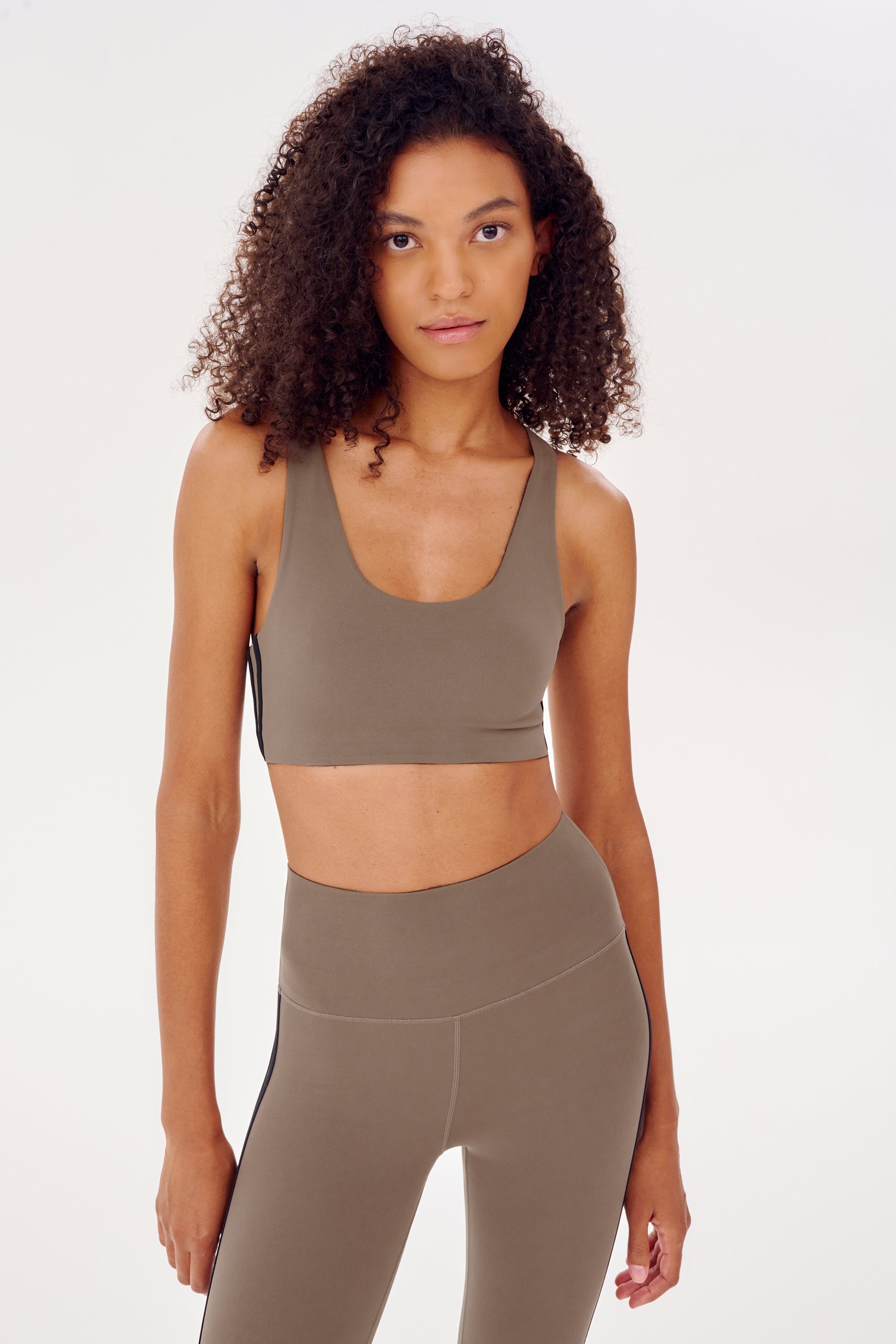 A woman wearing a grey SPLITS59 Ella Airweight sports bra and leggings.