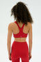 A person with curly hair is shown from the back, wearing the SPLITS59 Ella Airweight Bra in Pirate Red/Indigo against a plain light background.