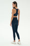 A woman wears the SPLITS59 Lexi Rigor Bra in Indigo/Blush with matching leggings and white sneakers, standing against a plain white background, facing away and looking to the side.