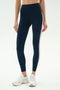 Model wears SPLITS59 Margot Rigor Legging in Indigo/Blush with a pink side stripe and white sneakers, standing against a plain light background.
