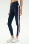 A person wearing SPLITS59 Margot Rigor Legging in Indigo/Blush and white athletic shoes stands against a plain background.