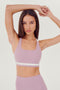 A woman wearing a Miles Rigor Bra in Blush/White by SPLITS59 designed for style and support during workouts.