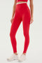 A person in Dual High Waist Airweight 7/8 - Pirate Red/White leggings and white sneakers by SPLITS59, perfect for hot yoga or Pilates, stands against a plain background.