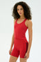 A woman with curly hair wears the SPLITS59 Ashby Rib Crop in Pirate Red and matching shorts with black stripes, standing against a white background—ideal for workouts or casual wear.