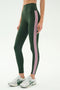 A person wearing SPLITS59's Margot Rigor Legging in Military/Blush with white athletic shoes, standing against a plain white background.