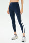 Someone wearing the SPLITS59 Miles High Waist Rigor 7/8 leggings in Indigo/White, paired with grey sneakers, stands against a plain background.