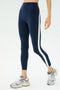 A person wearing SPLITS59 Miles High Waist Rigor 7/8 leggings in indigo/white and gray sneakers stands against a plain light background.