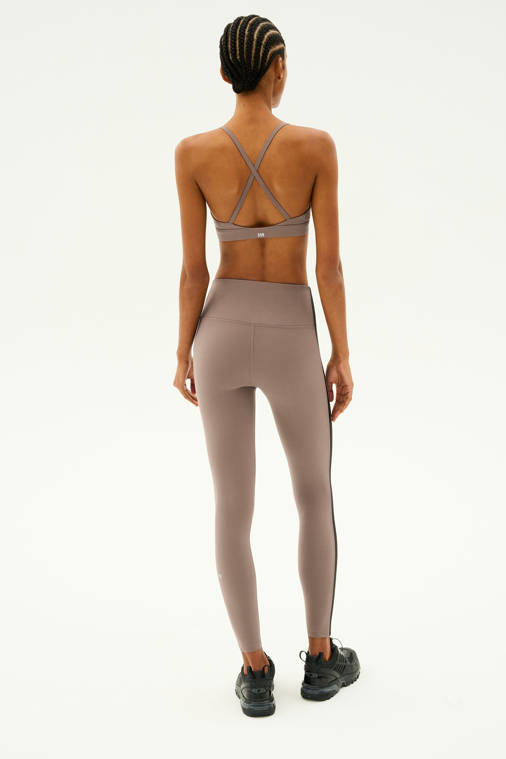 A person wearing the SPLITS59 Theo Rigor Bra in Lentil and leggings, made from ultra-luxe fabric designed for multi-sport performance, faces away from the camera.