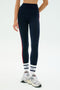 A person wearing SPLITS59 Ella High Waist Airweight 7/8 leggings in Indigo/Pirate Red, paired with white and navy socks and white sneakers—perfect for hot yoga—stands against a plain background.