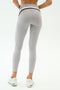 Person stands with back to camera, highlighting a sculpted look in SPLITS59 Emerson Airweight High Waist leggings in Dove Grey/Indigo and white sneakers against a plain backdrop—ideal for hot yoga or everyday wear.
