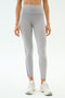 A person models SPLITS59 Emerson Airweight High Waist leggings in Dove Grey/Indigo—featuring a thin black side stripe and a sculpted fit—paired with white sneakers, perfect for hot yoga.