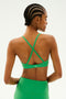 Sporting a SPLITS59 Theo Rigor Bra in the Grass color, this person highlights the ultra-luxe Rigor fabric engineered for multi-sport performance, with hair styled in cornrows against a plain background.