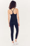 A woman seen from behind, wearing a SPLITS59 Airweight Tank in Indigo and leggings with a red and white stripe, standing against a white background.