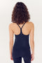 Woman seen from behind, wearing a SPLITS59 Airweight Tank in Indigo and leggings, standing against a white background.