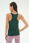 A woman poses with her back to the camera, wearing the SPLITS59 Kiki Rib Tank Full Length in Military and light pink leggings—ideal for yoga or running—against a plain light background.