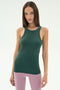 A woman with straight brown hair models the SPLITS59 Kiki Rib Tank Full Length - Military, paired with light pink leggings, perfect for yoga, standing against a plain white background.