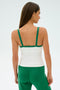 A woman with long hair stands with her back to the camera, wearing the SPLITS59 Monah Rigor Tank in White/Arugula, paired with matching green pants. Crafted from a comfortable nylon-spandex blend, the outfit complements the plain background.