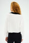 A person with curly hair, wearing the SPLITS59 Joan Fleece Polo Sweatshirt in White/Black and paired with black leggings, faces away from the camera.