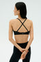 A woman stands with her back to the camera, arms crossed, wearing the SPLITS59 Theo Rigor Bra - Black and leggings—ideal for multisport performance thanks to its super soft Rigor fabric.