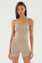 A woman with straight brown hair wears the SPLITS59 Ashby Rib Crop in beige, paired with matching high-waisted shorts, standing against a plain light background.