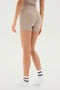 A person is standing with their back to the camera, showcasing the classic design of their beige Theo Rib Short - Latte by SPLITS59, complemented by white socks with black stripes.