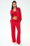 A woman stands in a relaxed pose wearing the SPLITS59 Hayes Varsity Rigor Jacket in Pirate Red, paired with a red crop top, red stretch wide-leg pants, and white sneakers against a plain white background.
