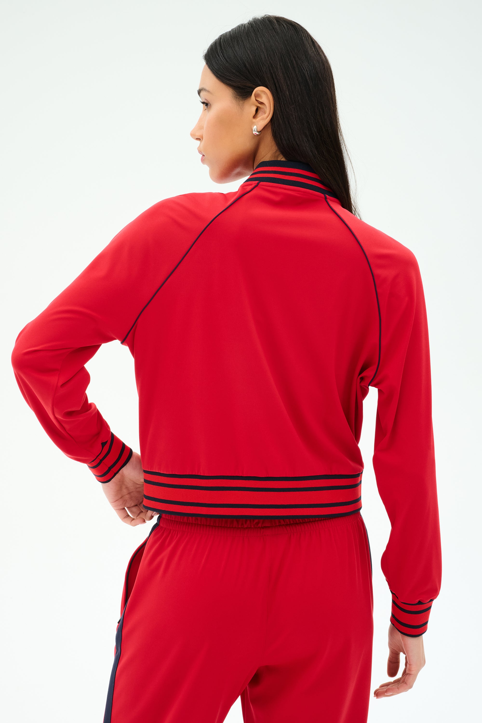 A woman in the SPLITS59 Hayes Varsity Rigor Jacket in Pirate Red.