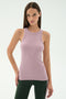 A woman stands against a plain white background wearing the SPLITS59 Kiki Rib Tank Full Length in Blush and dark green pants.