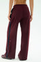 A person stands with their back to the camera, wearing SPLITS59's Luca Airweight Trouser with Stripe in Dark Cherry/Indigo, crafted from a comfy nylon-spandex blend, paired with matching shoes.