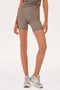 A woman wearing the SPLITS59 Ella High Waist Airweight Short in Lentil/Black with a side stripe and sneakers.