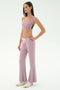 A woman, facing right against a plain white background, wears the SPLITS59 Blaire Rib Pant in Blush with a matching lilac modal-spandex sports bra and white sneakers.