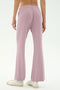 Model wears the SPLITS59 Blaire Rib Pant in Blush, showcasing the light purple flared silhouette made from soft modal-spandex, styled with white sneakers and photographed from behind against a plain backdrop.