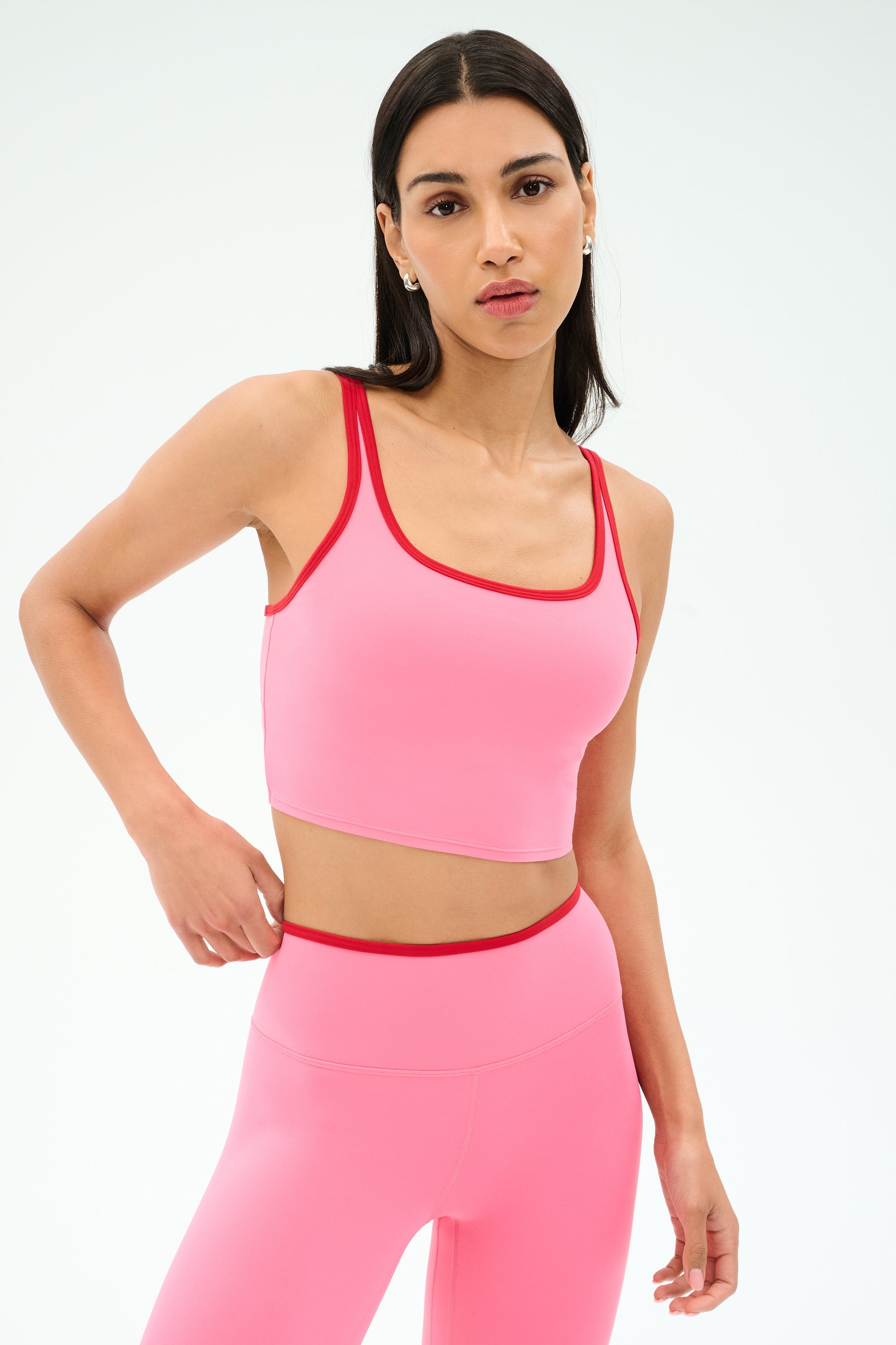 A woman models the SPLITS59 Cait Rigor Bralette in Strawberry/Pirate Red, crafted from a comfy nylon-spandex blend, paired with matching leggings against a plain white background.