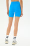 Model wears the SPLITS59 Ella High Waist Airweight Short in Riviera/White, paired with white socks featuring black stripes and white sneakers, all set against a white background.