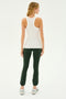 A woman stands facing away, dressed in a SPLITS59 Kiki Rib Tank Full Length in white, dark green leggings, and white sneakers, ready for some gym workouts.