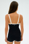 A person wearing the SPLITS59 Monah Rigor Jumpsuit, a black and white one-piece outfit, stands with their back to the camera against a plain backdrop.
