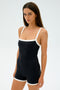 A person in the Monah Rigor Jumpsuit - Black/White by SPLITS59, made from stretchy spandex, stands against a plain background.