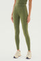 A person wearing SPLITS59's Airweight High Waist Legging in Olive, made from a comfortable nylon-spandex blend, paired with beige athletic shoes. The upper body is partially visible against a white background.