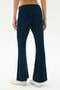Person wears SPLITS59's Blaire Rib Pant in Indigo—dark blue, flared, soft modal fabric—paired with white sneakers. Shown waist down against a plain light background.